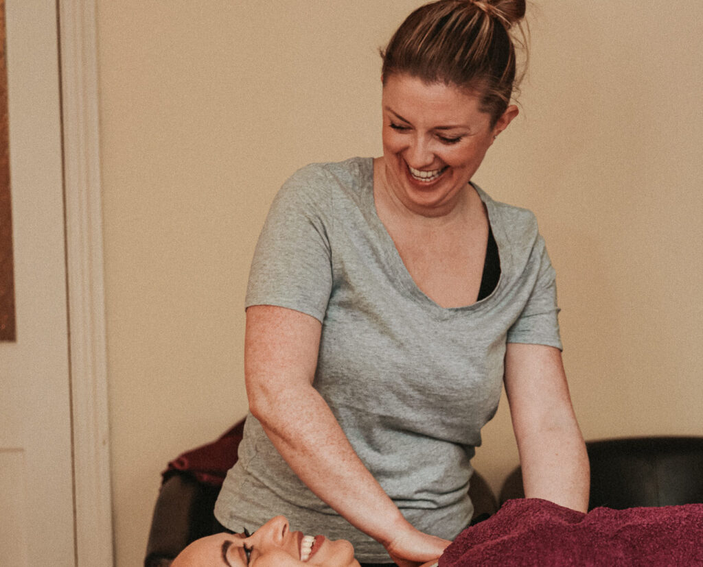 Voice and Body Specialist Gemma Boaden starting soft tissue massage on a client wearing a red towel