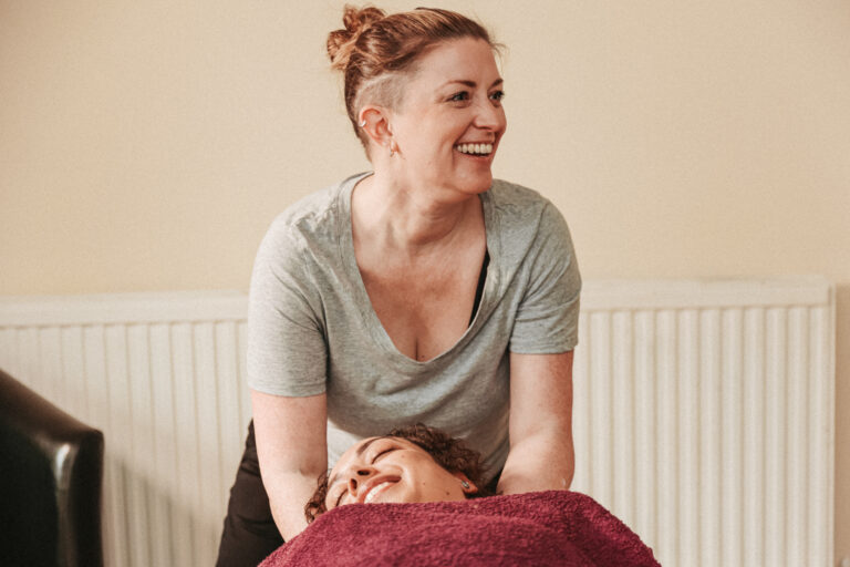 Voice and Body Specialist Gemma Boaden starting soft tissue massage on a client wearing a red towel - front angle